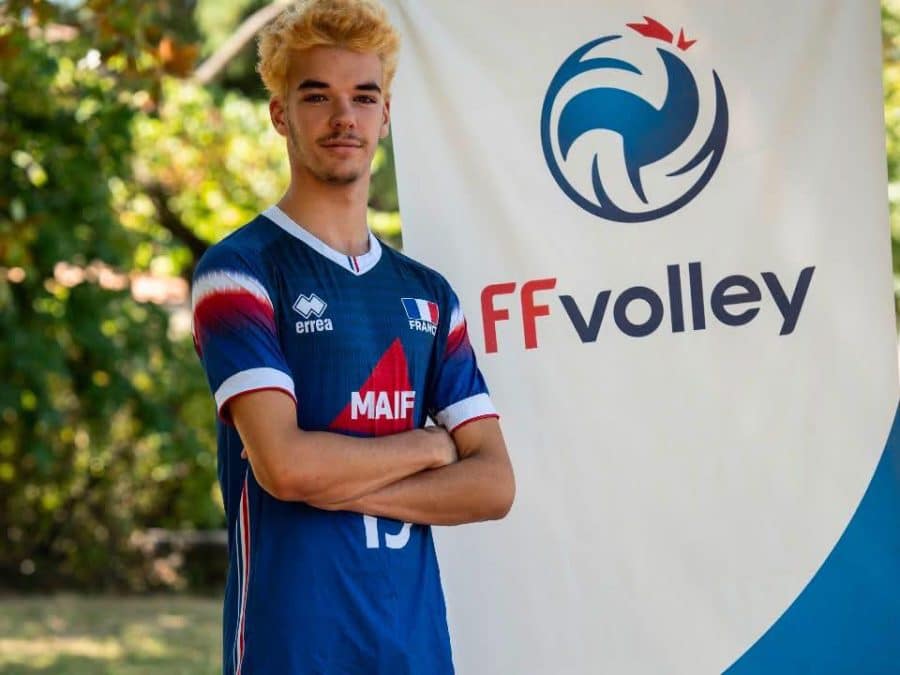 Lino Roques en maillot de l’équipe de France U18, devant une bannière FFvolley